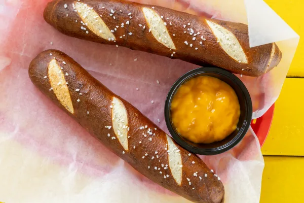 Two salted pretzel sticks with cheese dipping sauce