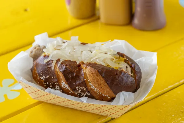 Hot dog topped with chopped onions and mustard in a dark bun