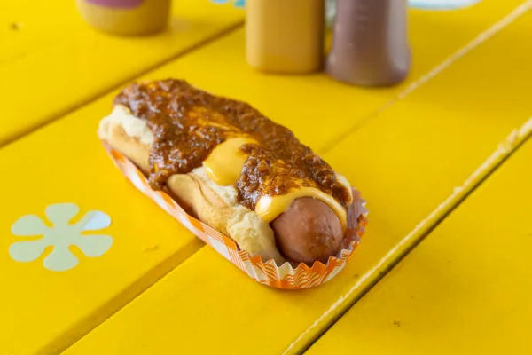 Chili cheese hot dog in a bun on a yellow table