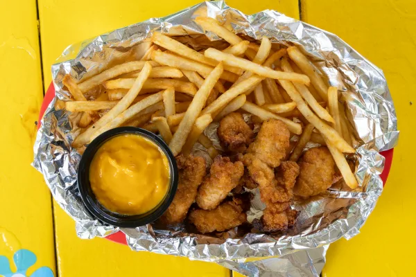 French fries and chicken tenders with a cup of cheese sauce