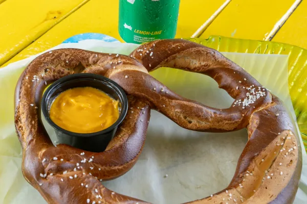 Salted soft pretzel with cheese dip and Sprite