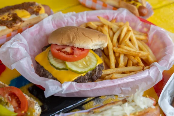 Cheeseburger topped with lettuce, tomato, and pickles beside French fries